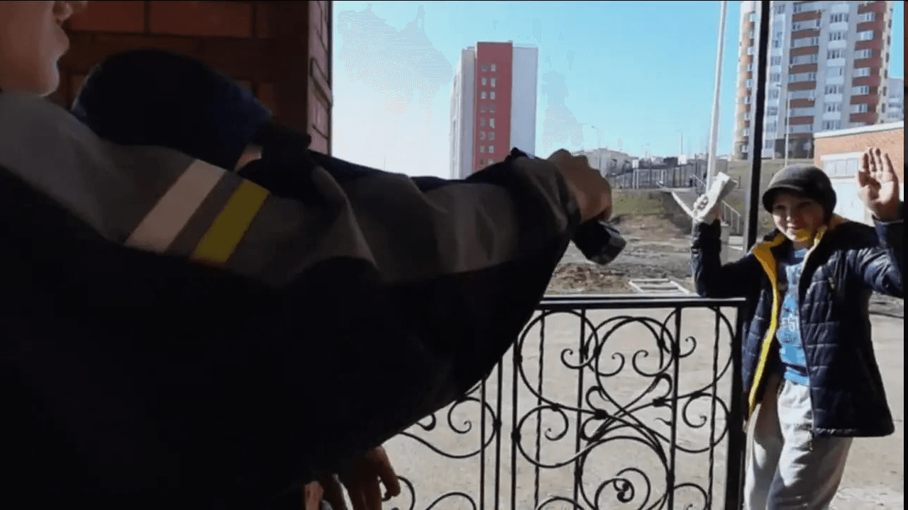 Двое людей направляют игрушечное оружие на человека, стоящего с поднятыми руками и банкнотами